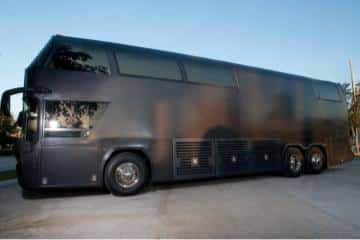 a large black bus parked in a parking lot.