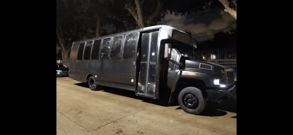 a black party bus parked on the side of the road.