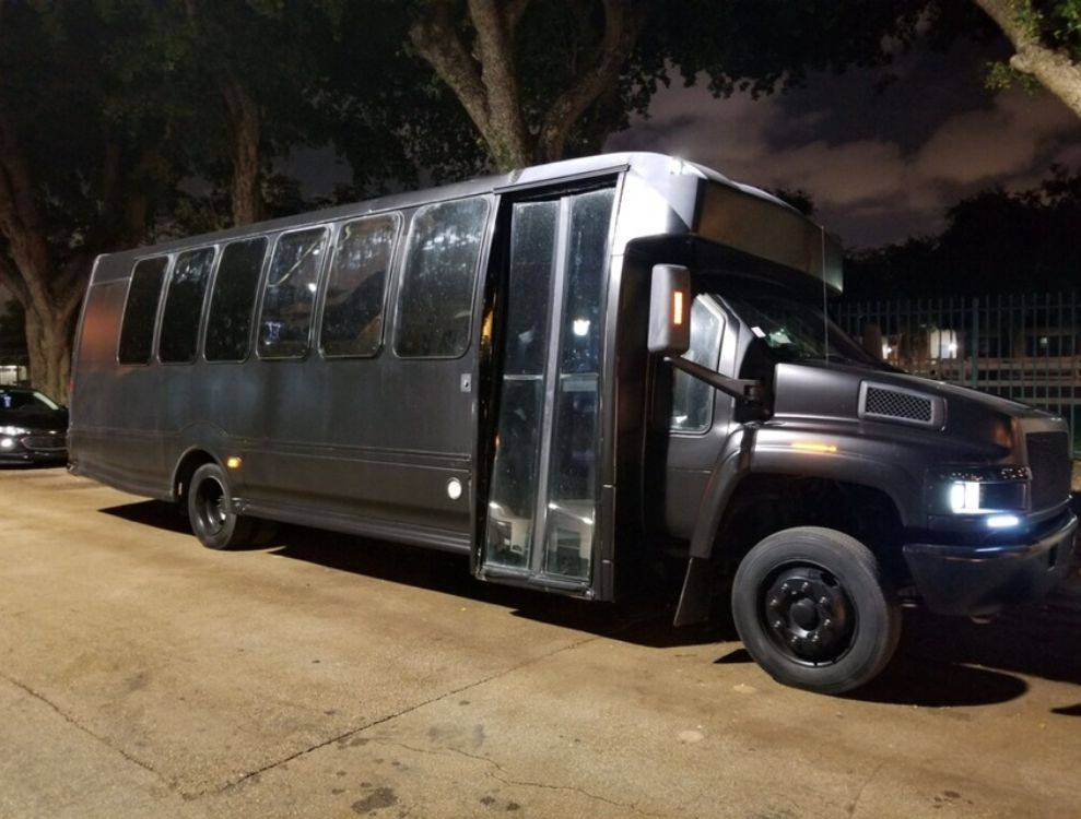 a black bus is parked on the side of the road.