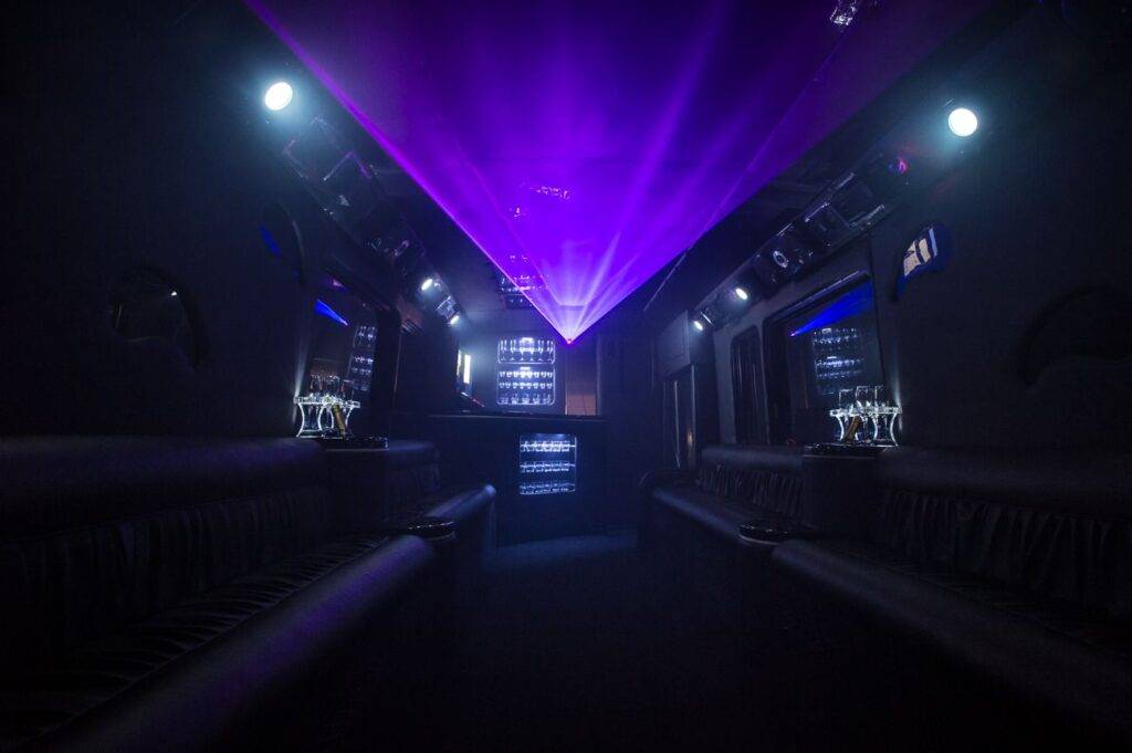 a dimly lit party bus with purple lights on the ceiling.