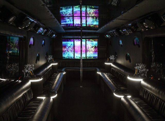 a dimly lit party bus with black leather seats.